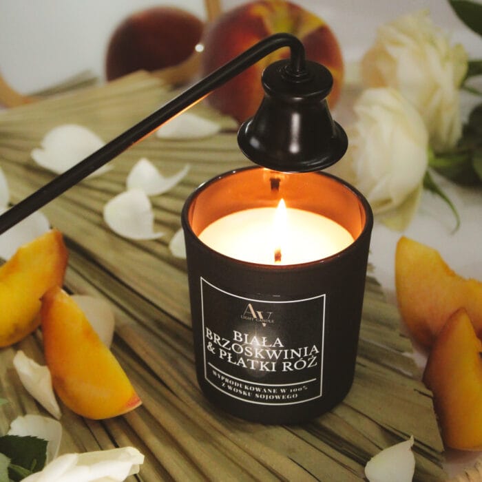 Świeca AV Light Candle Biała Brzoskwinia & Płatki Róż 130 ml zapalona pod lampą z knotem, na tle świeżych brzoskwiń i białych róż