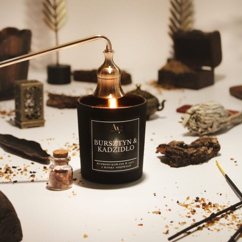 Świeca Bursztyn & Kadzidło AV Light Candle 130 ml zgaszona eleganckim gasidłem, w stylizowanej aranżacji orientalnej