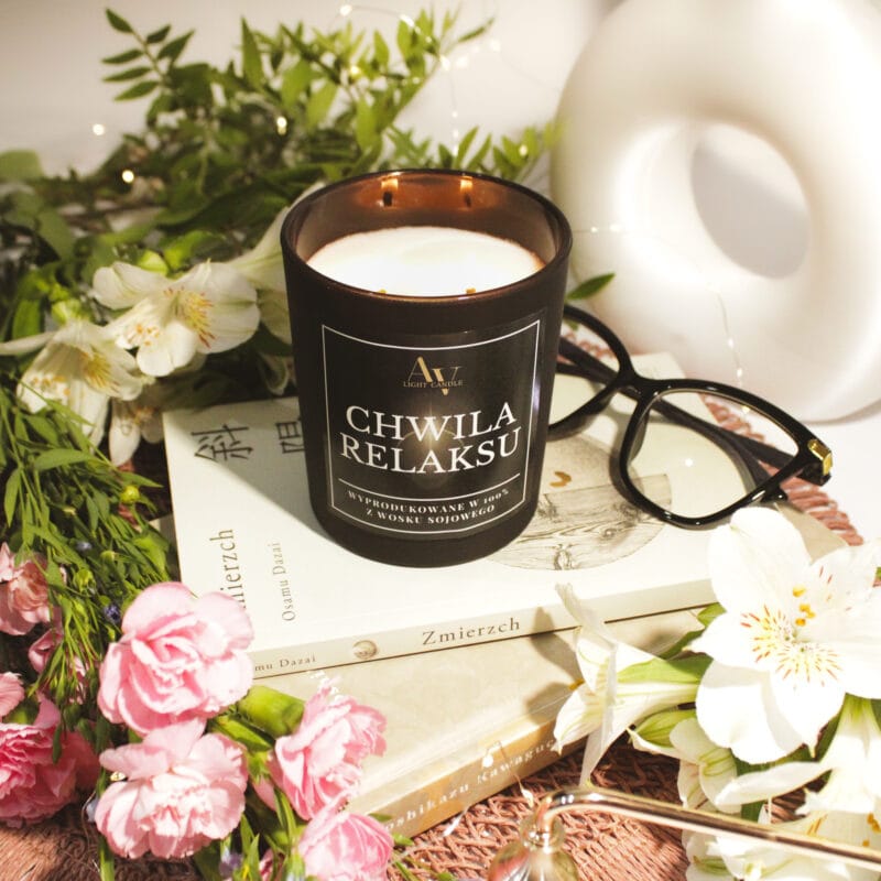 Zgaszona świeca sojowa AV Light Candle Chwila Relaksu Lumor w matowym czarnym szkle w aranżacji z książkami i kwiatami