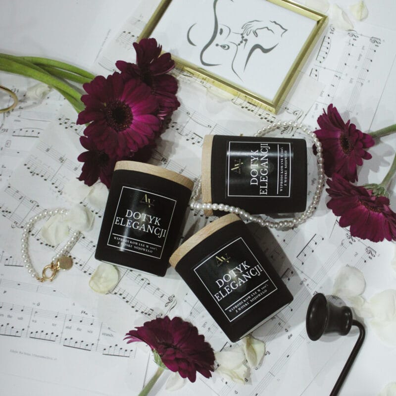 trzy świece Dotyk Elegancji AV Light Candle Ember 130 ml w kompozycji z ciemnymi kwiatami i perełkami na tle nut muzycznych