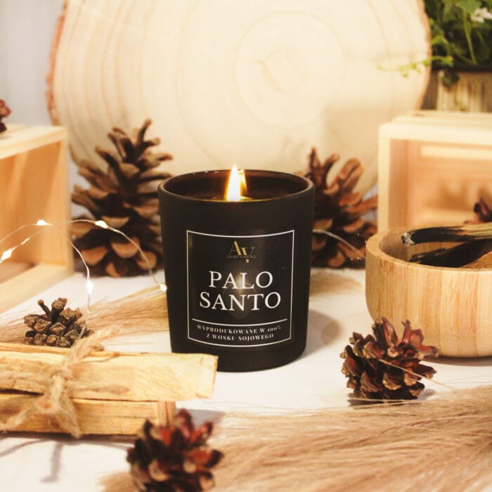 Świeca Palo Santo AV Light Candle zapalona, otoczona szyszkami i drewnem