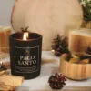 Świeca Palo Santo SENSE – zapalona wśród szyszek i drewna, aranżacja z boku