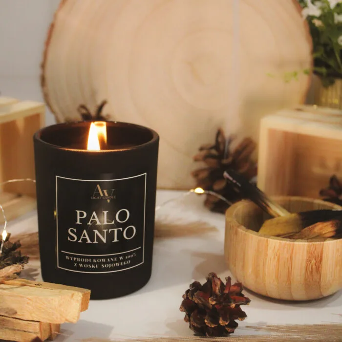 Świeca Palo Santo SENSE – zapalona wśród szyszek i drewna, aranżacja z boku