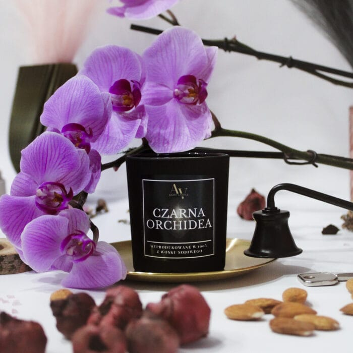 Świeca Czarna Orchidea AV Light Candle z orchideą w tle i eleganckim wygaszaczem płomieni.