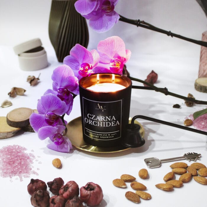Zapalone dwa knoty świecy Czarna Orchidea z kolekcji Lumor otoczone fioletową orchideą
