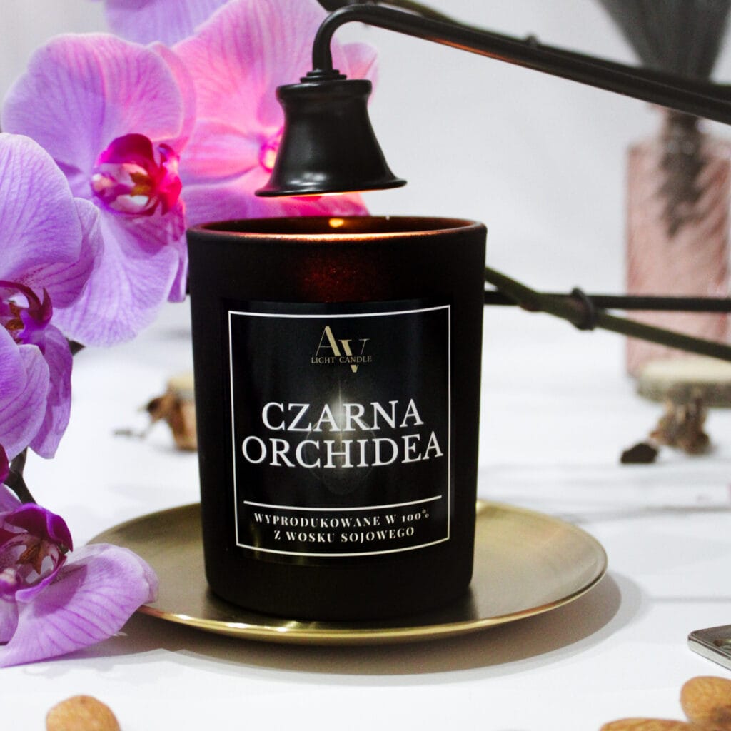 Świeca sojowa Czarna Orchidea 200 ml z kolekcji Sense AV Light Candle na złotej tacy w otoczeniu orchidei