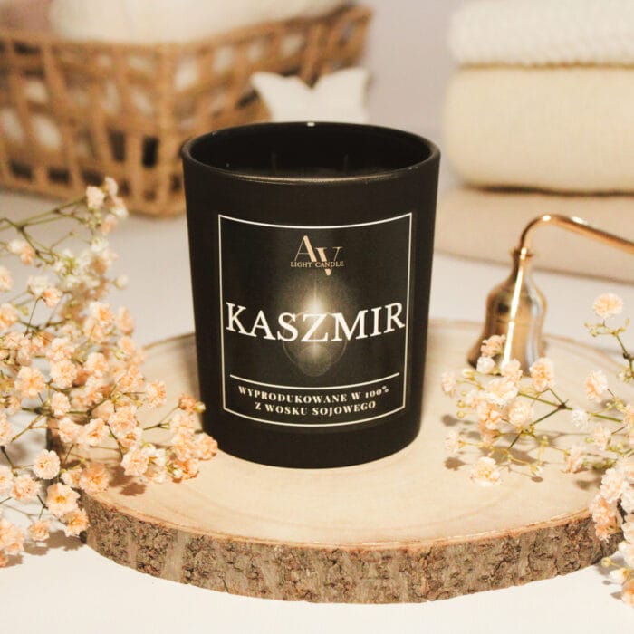 Zbliżenie na zapaloną świecę Kaszmir AV Light Candle 280 ml – ciepła, kaszmirowa atmosfera w otoczeniu miękkich materiałów