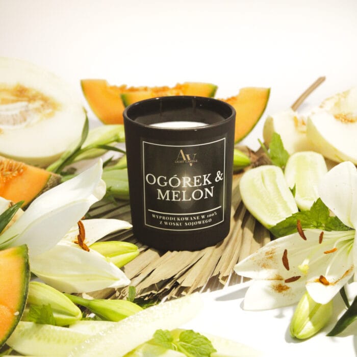 Czarna świeca Ogórek & Melon Lumor 280 ml w otoczeniu świeżego ogórka, melona i kwiatów
