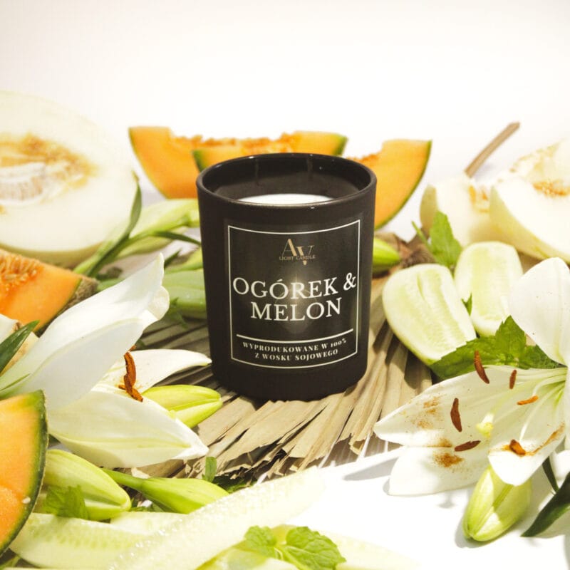 Czarna świeca Ogórek & Melon Lumor 280 ml w otoczeniu świeżego ogórka, melona i kwiatów