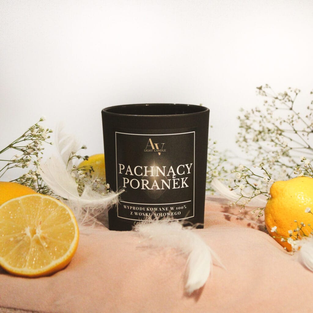 Świeca sojowa AV Light Candle Pachnący Poranek Lumor 280 ml z dwoma knotami, czarny matowy słoik na tle cytryn i białych piór.