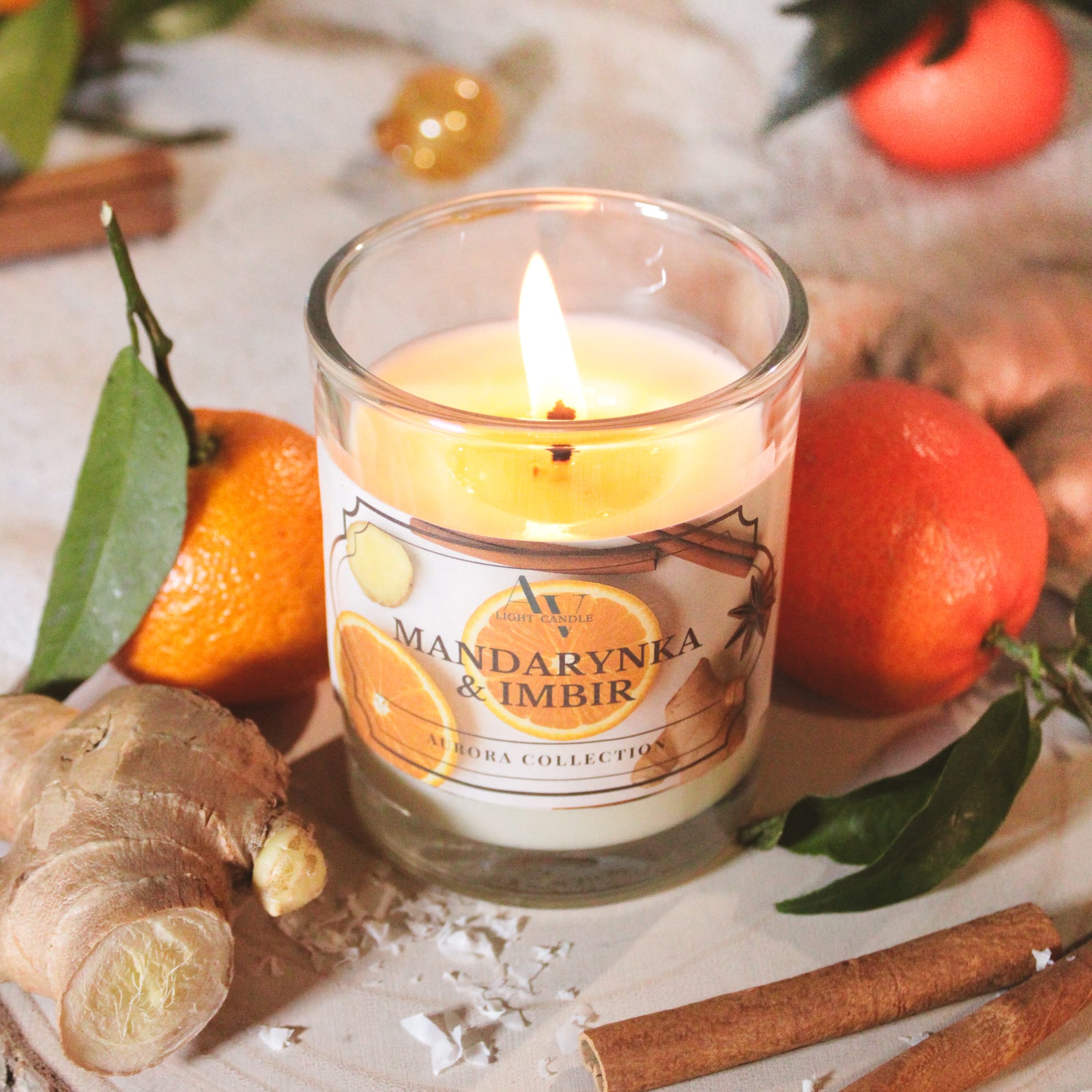 Zapalona świeca Mandarynka & Imbir 200 ml – zbliżenie na etykietę z cytrusami, korzeniem imbiru i płonącym knotem
