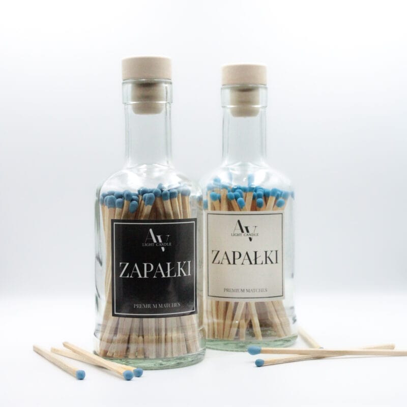 Dwie szklane butelki z długimi zapałkami AV Light Candle z niebieskimi główkami, w wersji z czarną i kremową etykietą, ustawione na białym tle.