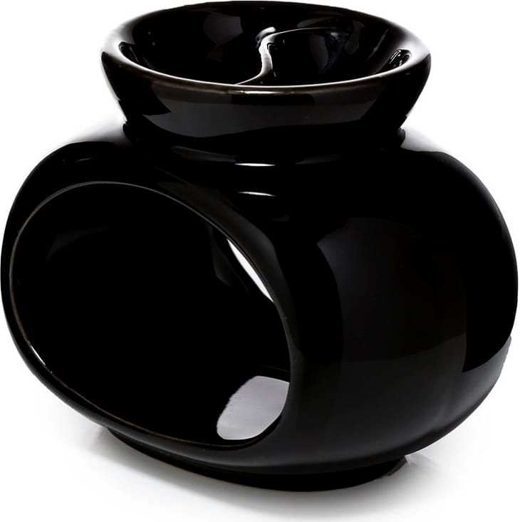 Czarny ceramiczny kominek na wosk zapachowy o organicznej formie, który równomiernie topi wosk i subtelnie uwalnia aromat w nowoczesnym wnętrzu.